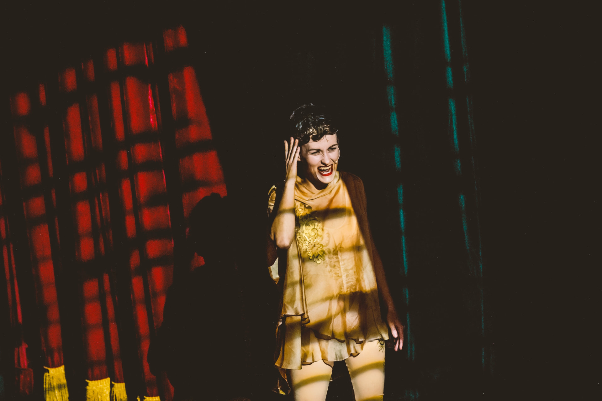 Performerka obnaŽENA zpívající na jevišti v dramatickém osvětlení